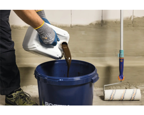 Vloeistof wordt in een emmer gegoten, een verfroller ligt ernaast