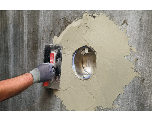 Vakman brengt plamuur aan op een muur om een uitsparing te vullen.