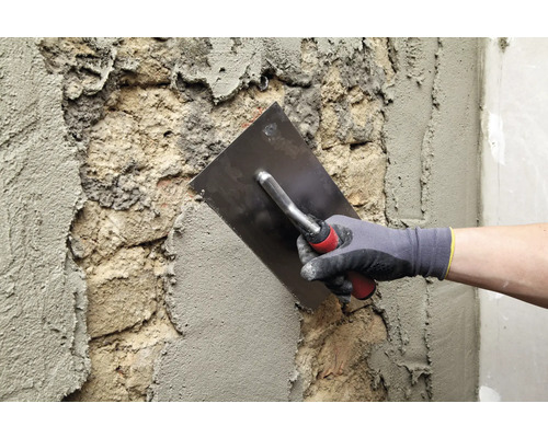 Metselaar bepleistert een muur met een pleisterspaan.
