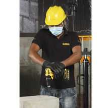 Vakman boort met een accuboormachine in een betonblok, terwijl hij beschermende kleding draagt.