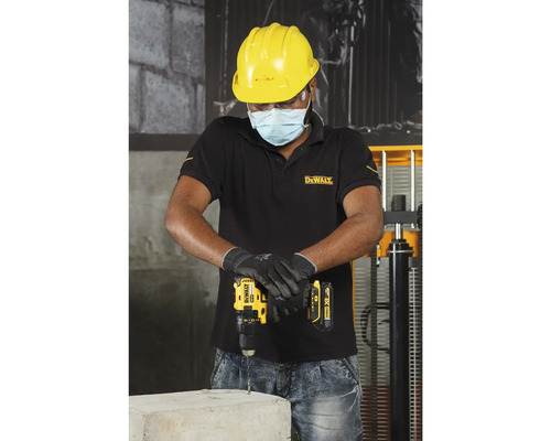 Vakman boort met een accuboormachine in een betonblok, terwijl hij beschermende kleding draagt.