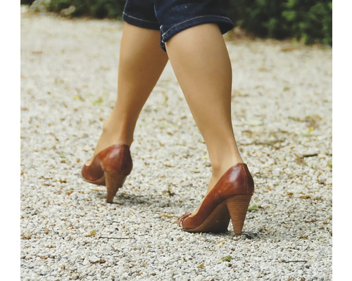 Vrouw loopt in leren schoenen met hak op grind