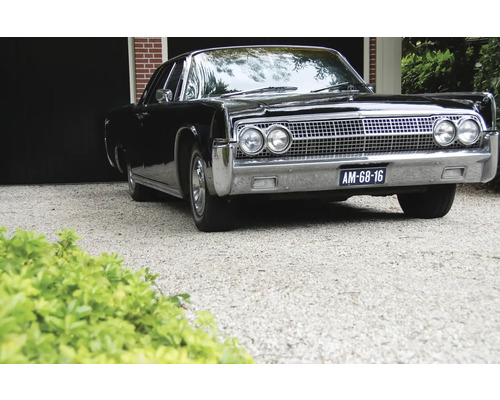 Zwarte oldtimer geparkeerd voor een garage
