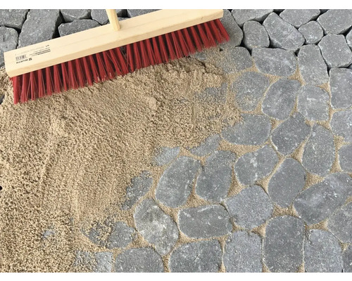 Bestratingsvoegen worden met een bezem en voegzand gevuld.