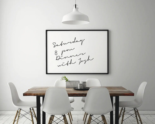 Eetkamer met houten tafel, witte stoelen en een ingelijste afbeelding aan de muur.