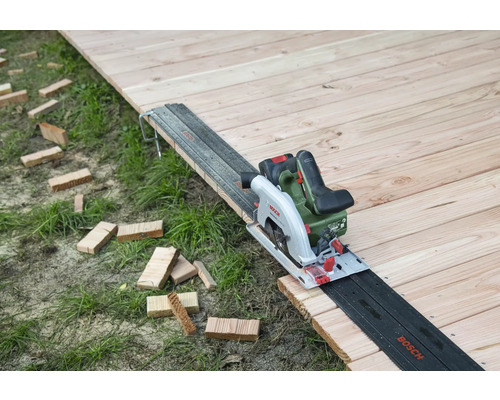 Accucirkelzaag op houten vloer met geleiderail en houten stukken