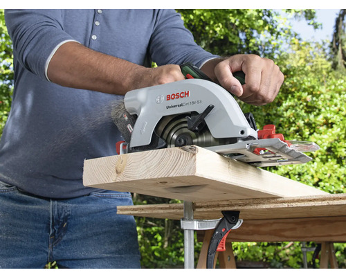 Een persoon zaagt een houten plank met een Bosch handcirkelzaag.