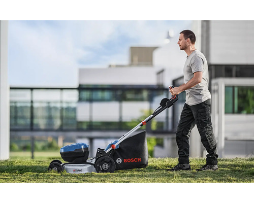 Man bedient een Bosch accugrasmaaier in de tuin.