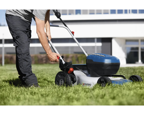 Een persoon gebruikt een accugrasmaaier op een gazon voor een huis.