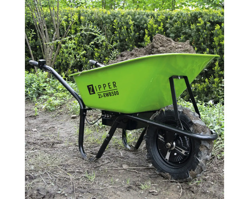 Groene kruiwagen gevuld met aarde in de tuin