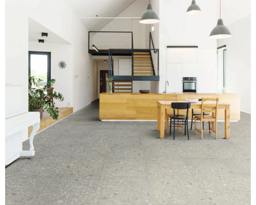Lichte woonkamer met grijze vloertegels, keukentafel en trap