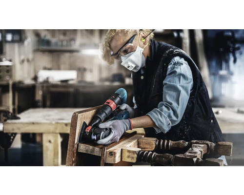 Vrouw schuurt een stoel met elektrisch gereedschap in een werkplaats