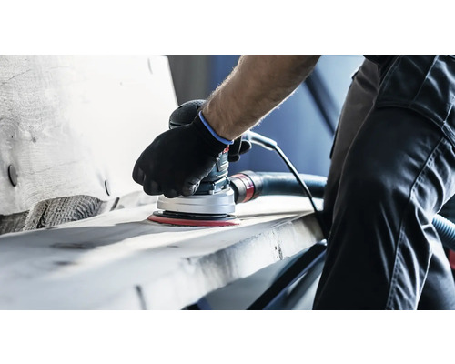 Een persoon schuurt een werkstuk met een excentrische schuurmachine.