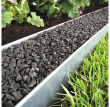 Tuin met gazon, planten en metalen borderrand gevuld met siergrind