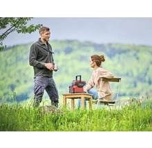 Een stel ontspant buiten met een powerstation op een houten tafel.