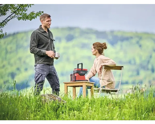 Een stel ontspant buiten met een powerstation op een houten tafel.