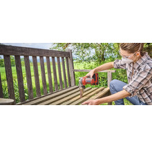 Een vrouw schuurt een houten bank met een Einhell bandschuurmachine.