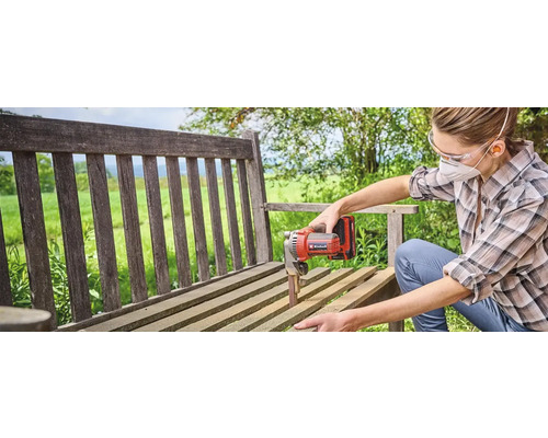 Een vrouw schuurt een houten bank met een Einhell bandschuurmachine.