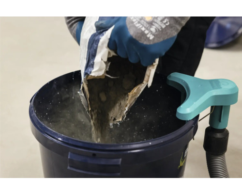 Iemand giet droog beton uit een zak in een emmer.