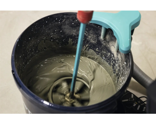 Mortel wordt in een emmer gemengd met een elektrische roerder