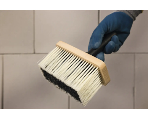 Behangborstel met houten handvat en borstelharen wordt door een hand vastgehouden