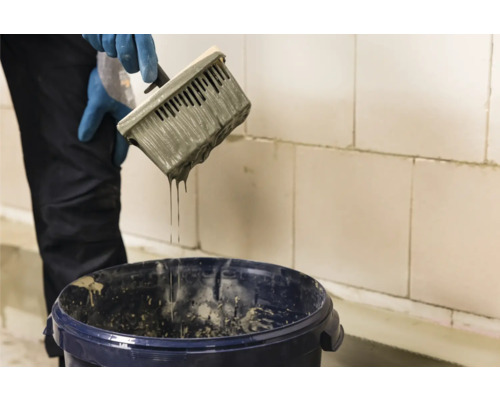 Metselaar met lijmspaan en emmer voor cellenbetonblokken