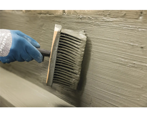 Het aanbrengen van pleister met een gevelborstel op een muur.