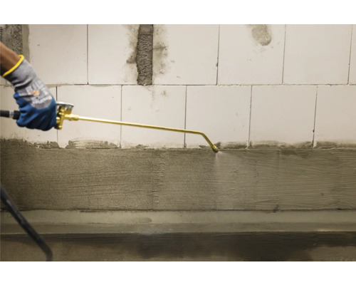 Aanbrengen van vloeibare afdichting met een spuitpistool op een betonnen muur