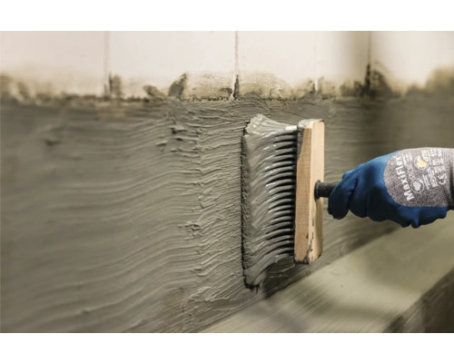 Lijm aanbrengen op een muur met een borstel