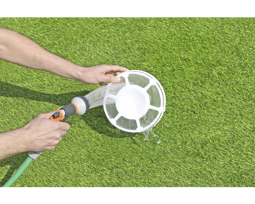 Reiniging van een zwembadskimmer met een tuinslang op een gazon.