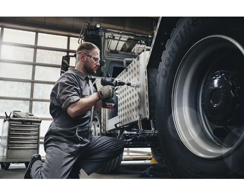 Een man werkt met een accuboormachine aan een voertuig.