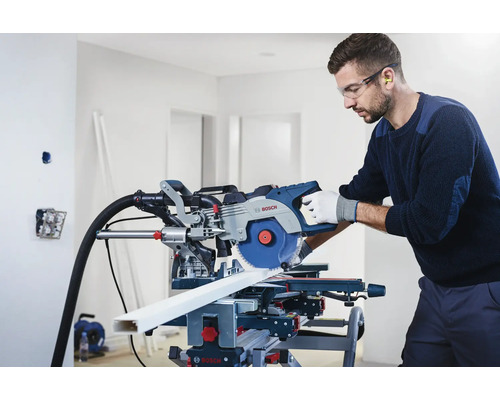 Man met veiligheidsbril en gehoorbescherming die een Bosch verstekzaag gebruikt om een werkstuk te zagen