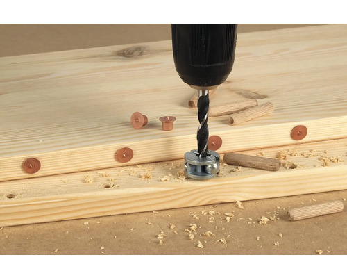 Boormachine met deuvelboor boort gaten in houten planken voor deuvelverbindingen.