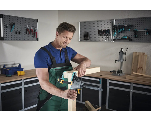 Man gebruikt eenhandsklem in een werkplaats om hout te bevestigen.
