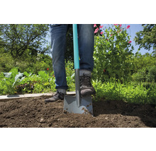 Persoon steekt spade in tuingrond