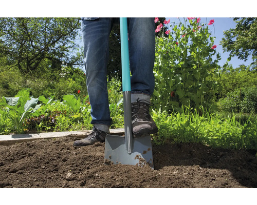 Persoon steekt spade in tuingrond