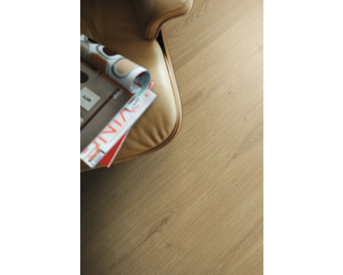 Close-up van een laminaatvloer met tijdschrift naast een fauteuil