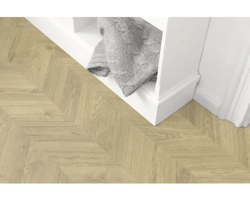 Lichte houten vloer in visgraatmotief naast een witte plank met een deken