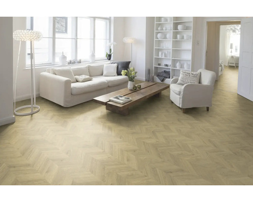 Lichte woonkamer met bank, fauteuil en visgraatparket