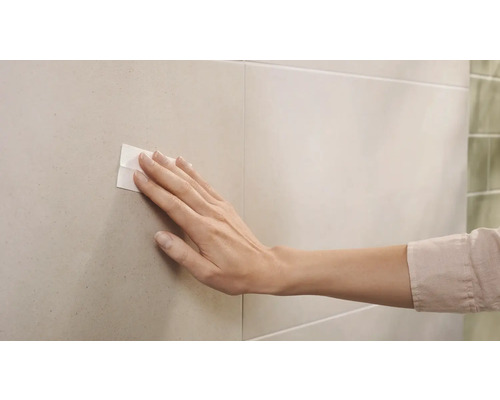 Vrouwenhand drukt plakstrip op tegel