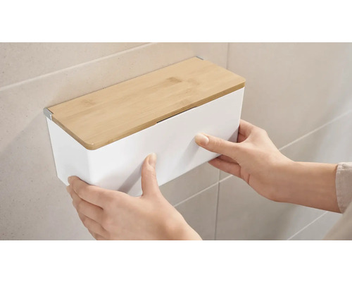 Persoon monteert een witte wandbox met bamboe deksel aan een muur