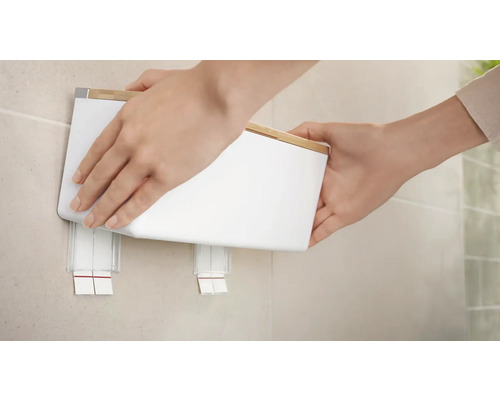 Persoon bevestigt een zeepdispenser aan de muur in de badkamer