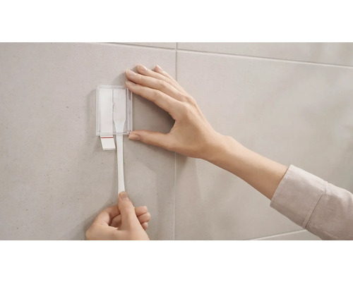 Applicatie van plakstrips op een betegelde muur