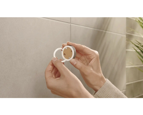 Een persoon bevestigt een magnetische bevestigingsknop aan een muur