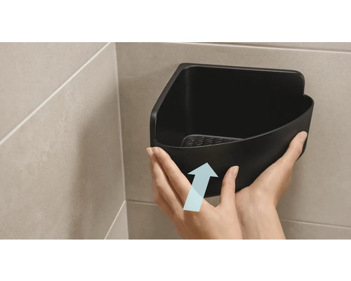 Iemand bevestigt een zwarte hoekplank in de badkamer.