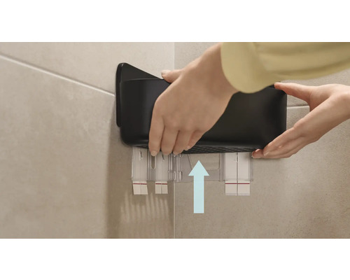 Iemand bevestigt een zwarte badkamerplank aan de muur.