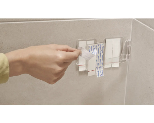 Persoon verwijdert beschermfolie van plakstrips op een wandmontage