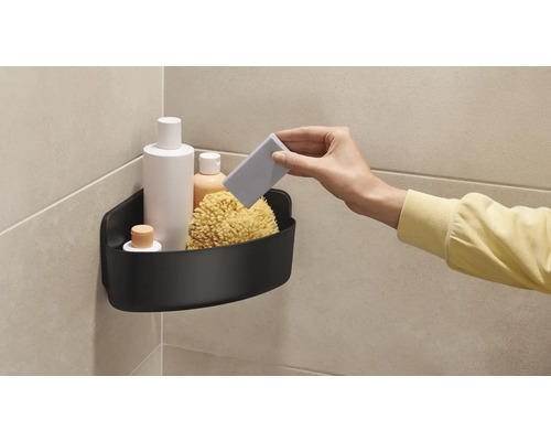 Hoek met zwarte doucherek, gevuld met badproducten en een badspons