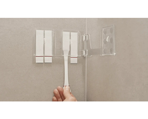 Transparante tandenborstelbeker met bevestigingsstrips op een badkamermuur