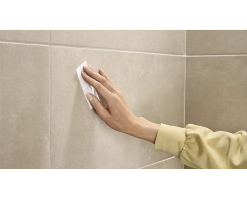 Een persoon reinigt tegels met een reinigingsdoekje.